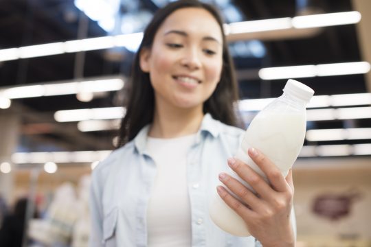 femme tenant une bouteille de lait entier ou demi-écrémé