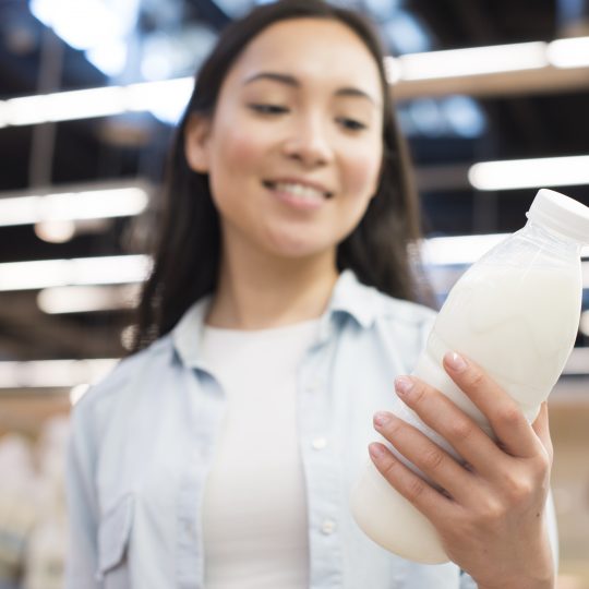 femme tenant une bouteille de lait entier ou demi-écrémé